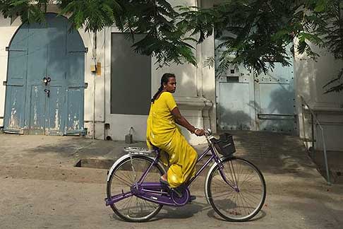 Traffico e atmosfere indiane - Donna con il Sari in bicicletta abito molto colorato tipoco indiano a Pondicherry in India width=