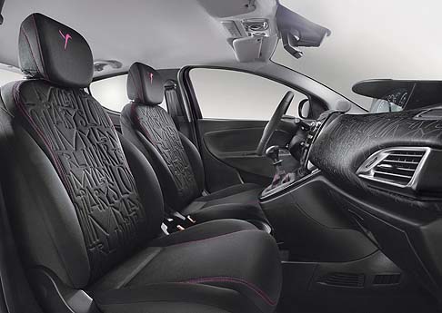 Lancia - Per tutte le tonalità esterne è disponibile un solo interno casual dove troviamo il volante in pelle, le finiture cromate della plancia e i sedili in tessuto nero con cuciture fucsia. width=