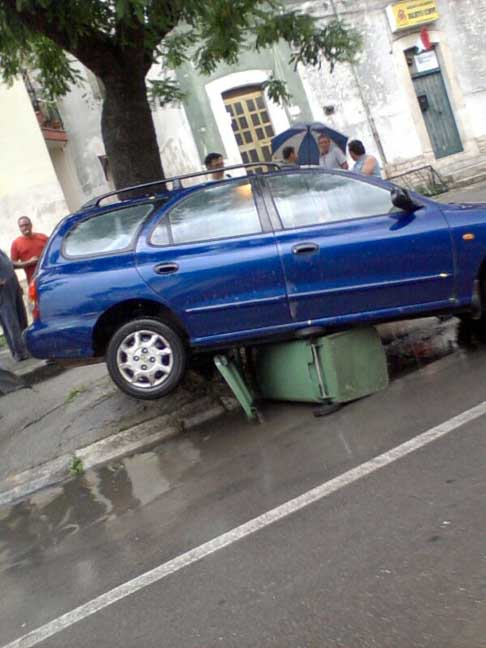 Nubifragio Sud Barese - Vettura station wagon danneggiata dalla forte pioggia, sopra al bidone della raccolta del vetro ad Acquaviva delle Fonti del 14 Giugno 2014 width=