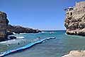 Atleti attraversano in difficoltà la passerella galleggiante e scogliera gremita di gente al Red Bull Cliff Diving World Siries 2025 a Polignano a Mare
